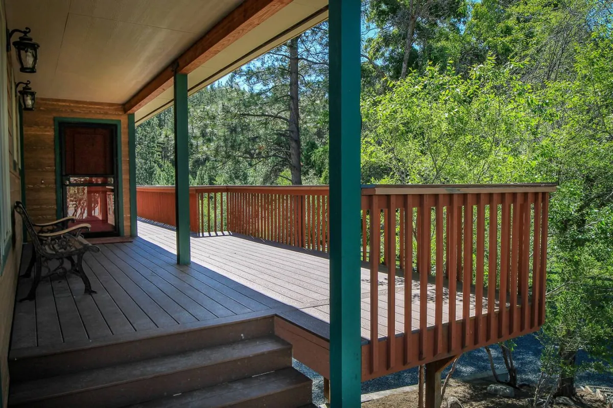A tranquil wooden deck surrounded by lush green foliage, featuring a welcoming bench for relaxing and soaking in the natural surroundings. The setting is perfect for unwinding with a drink, birdwatching, or enjoying sunsets after a day of exploring.